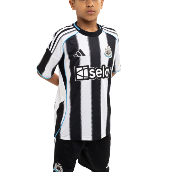 Young boy wearing a black-and-white striped soccer jersey with blue trim and sponsor logo, posing with hands behind back.