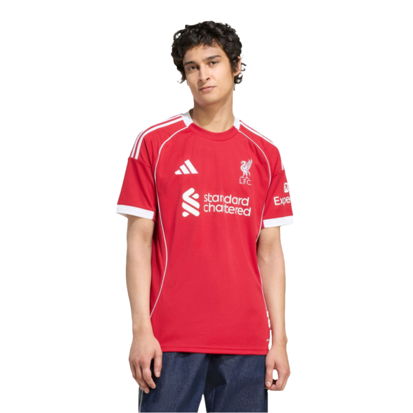 Young man wearing a red Liverpool FC jersey with sponsor logo, facing the camera in a neutral pose.