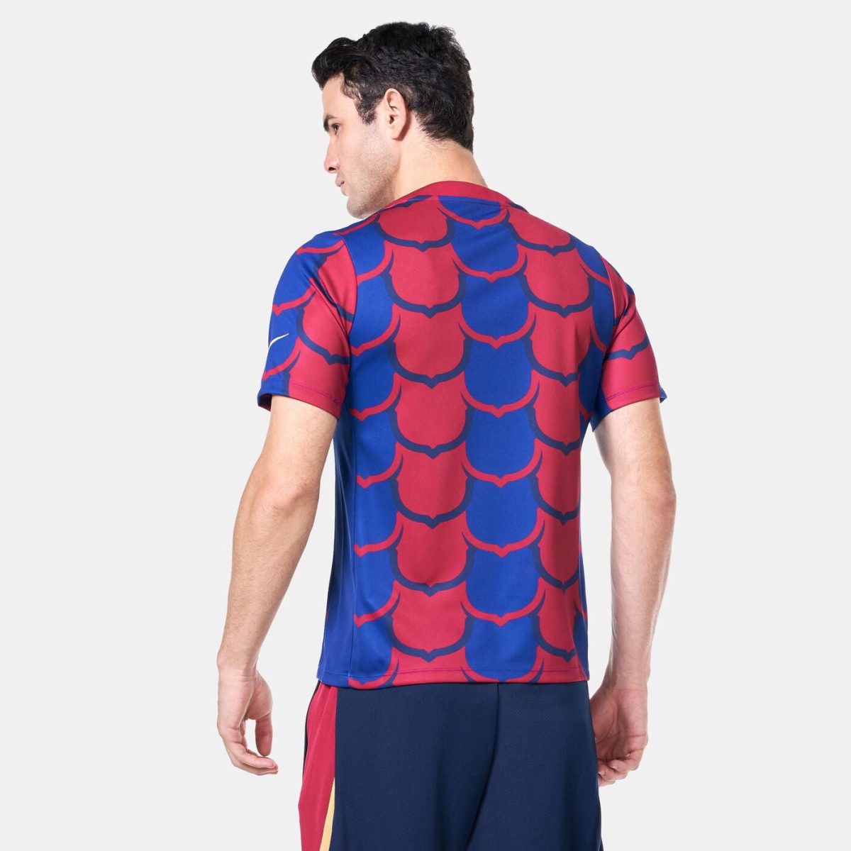 Back view of a man wearing a blue and red scale-pattern athletic shirt.