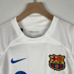 White polo shirt on a wooden hanger with a blue Nike swoosh and FC Barcelona crest on the chest area.