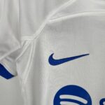 Close-up of white fabric with a blue Nike swoosh logo partially visible.
