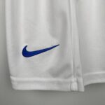 Close-up of white fabric with a blue Nike Swoosh embroidered near the lower left corner.