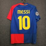 Blue Barcelona football jersey hanging on a hanger, 'MESSI' and large yellow number 10 on the back with a Champions League patch on the sleeve. The jersey has red and blue color blocks.