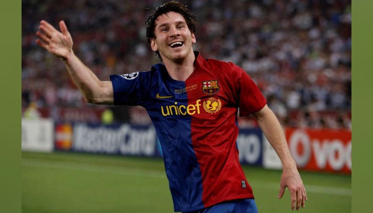 Soccer player in a Barcelona UNICEF jersey celebrating on the pitch with arms outstretched.