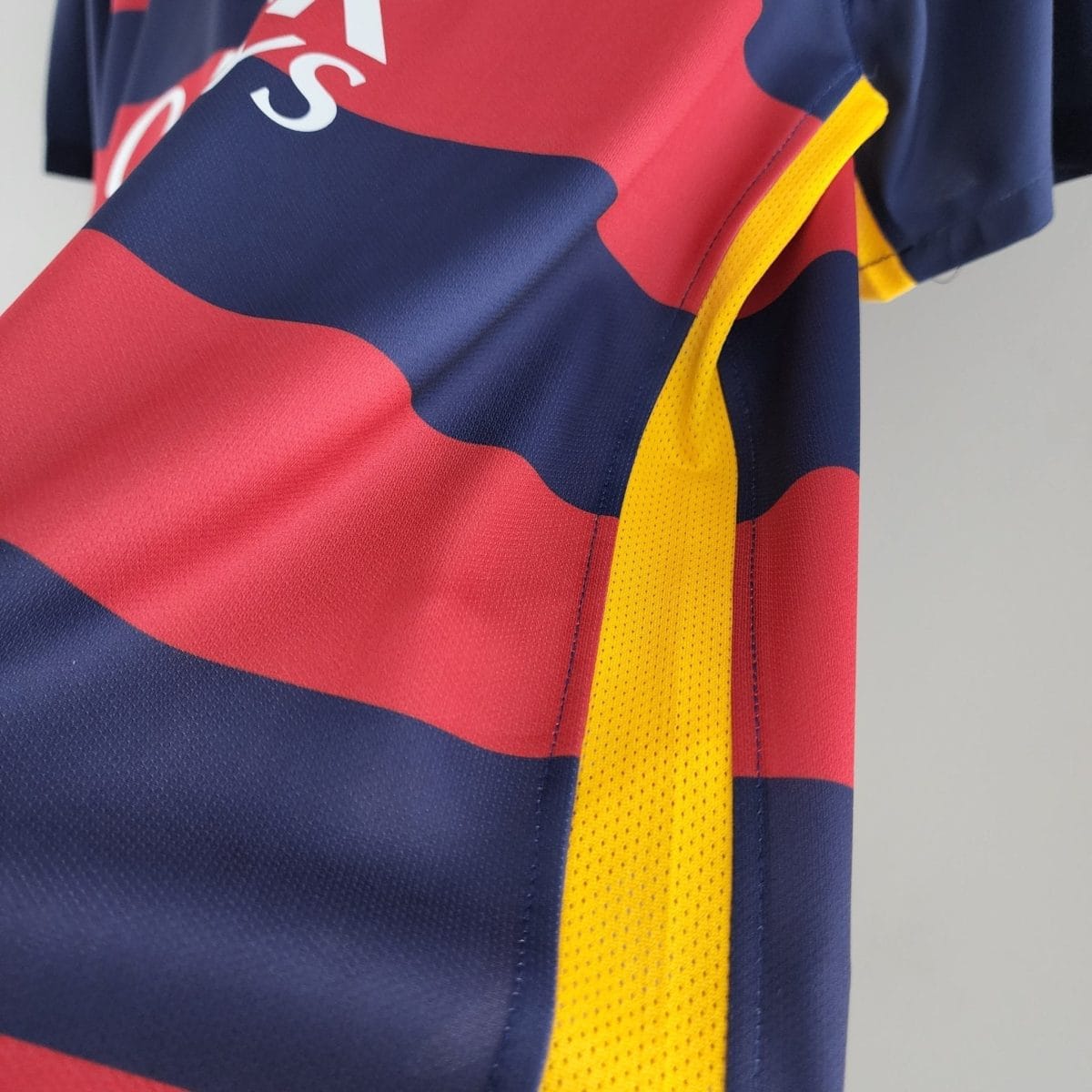 Close-up of a sports jersey with red and blue panels and a yellow strap/trim visible along the edge.
