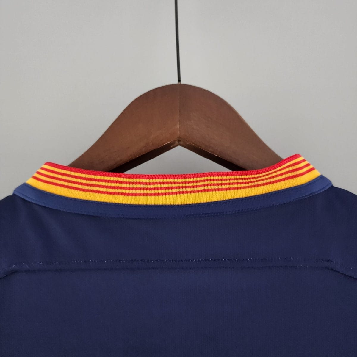 Blue garment on a wooden hanger with a bright red-yellow striped collar visible at the top edge.
