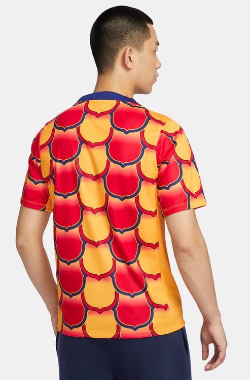 barcelona-gold-pre-match-jersey-2024-802169 | UAE SPORT STORE Back view of a man wearing a bright yellow short-sleeve shirt with a red scalloped wave pattern outlined in dark blue.