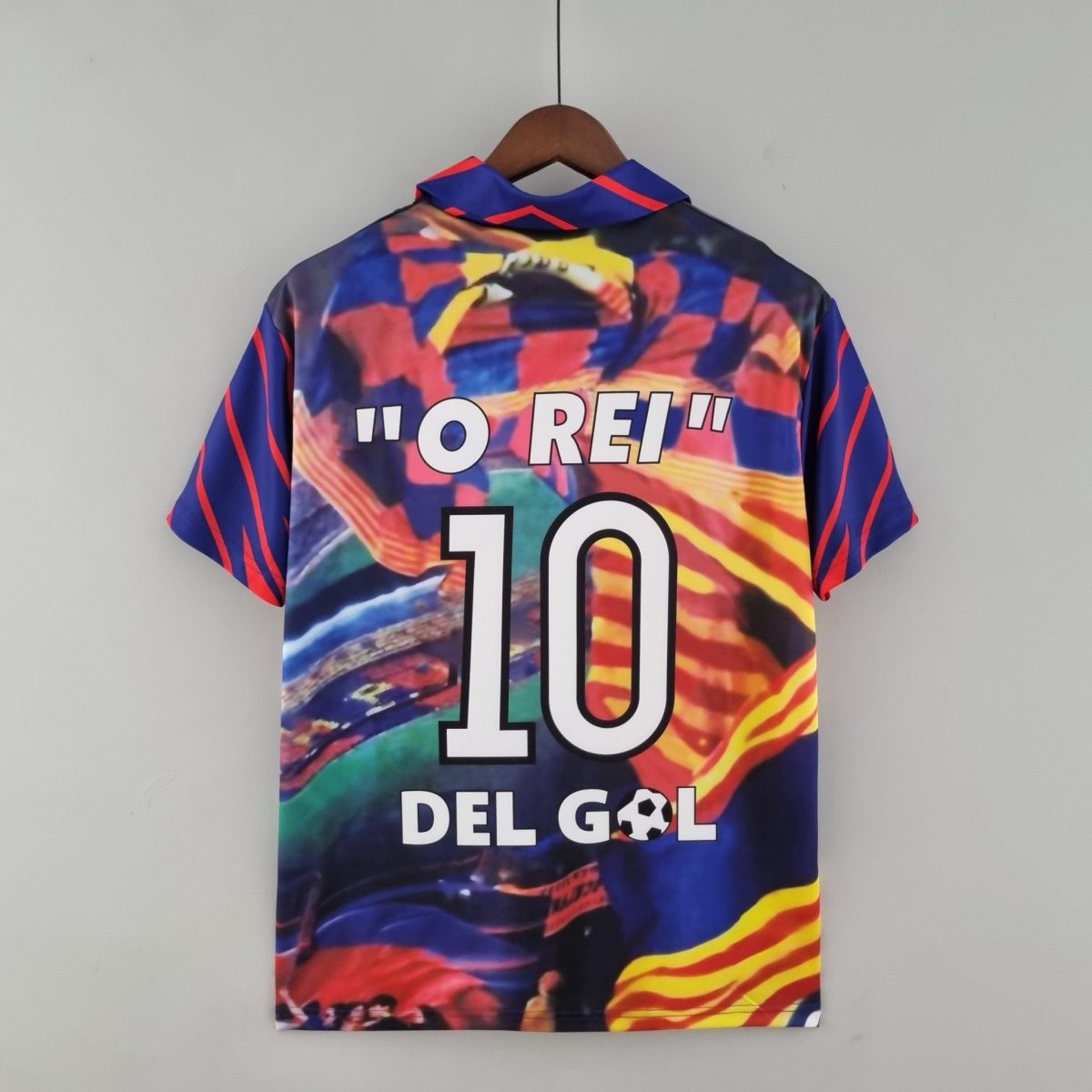 Bright, abstract-patterned shirt on a wooden hanger against a gray wall; large white text partially visible reading '10' on the front.