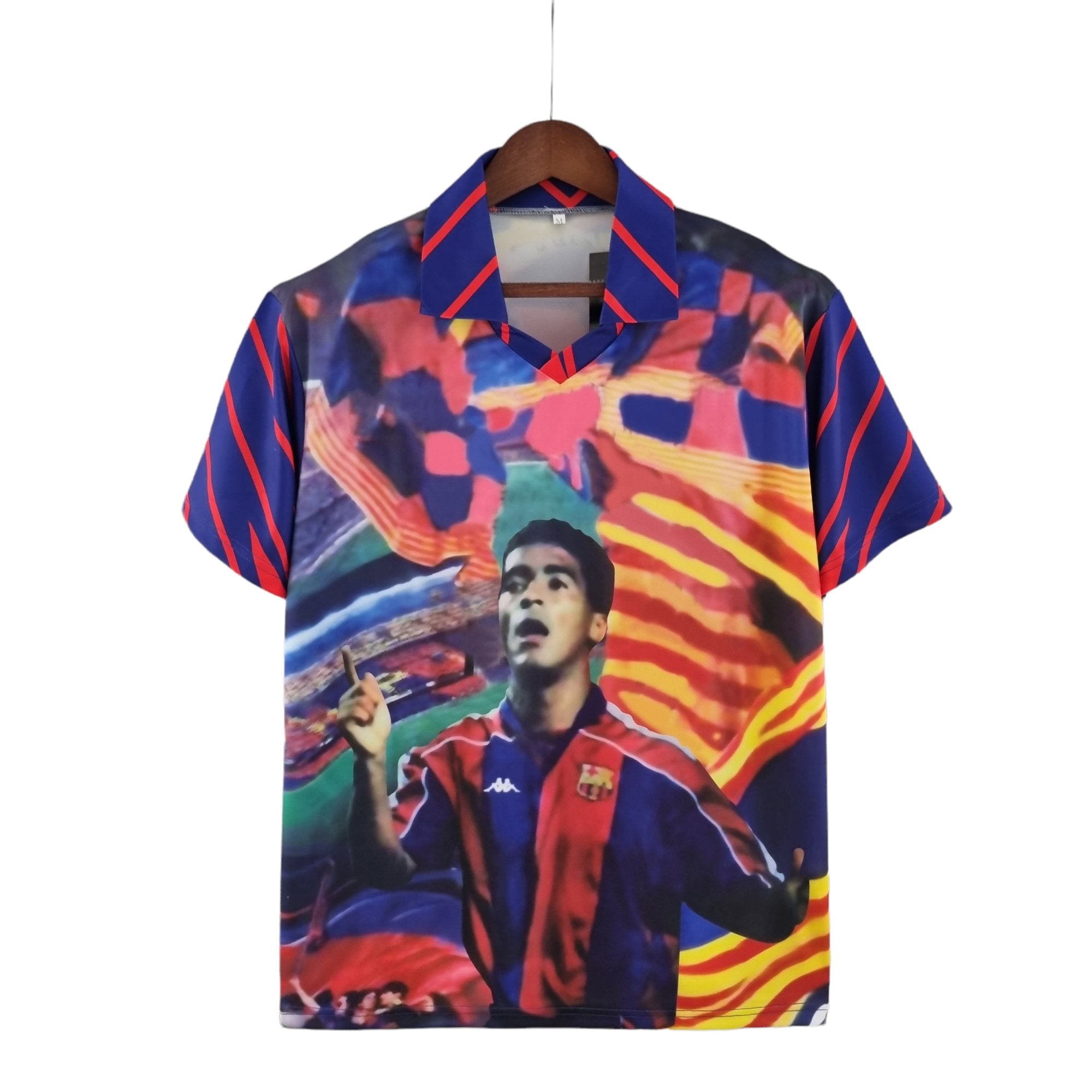 barcelona-home-classic-9394-romario-jersey-604146 | UAE SPORT STORE Colorful printed shirt on a wooden hanger, featuring a portrait and bold abstract patterns.