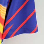 barcelona-home-classic-9394-romario-jersey-756285 | UAE SPORT STORE Close-up of blue fabric with orange diagonal stripe and a gradient yellow-to-orange area on the left, showing stitching on a garment edge.