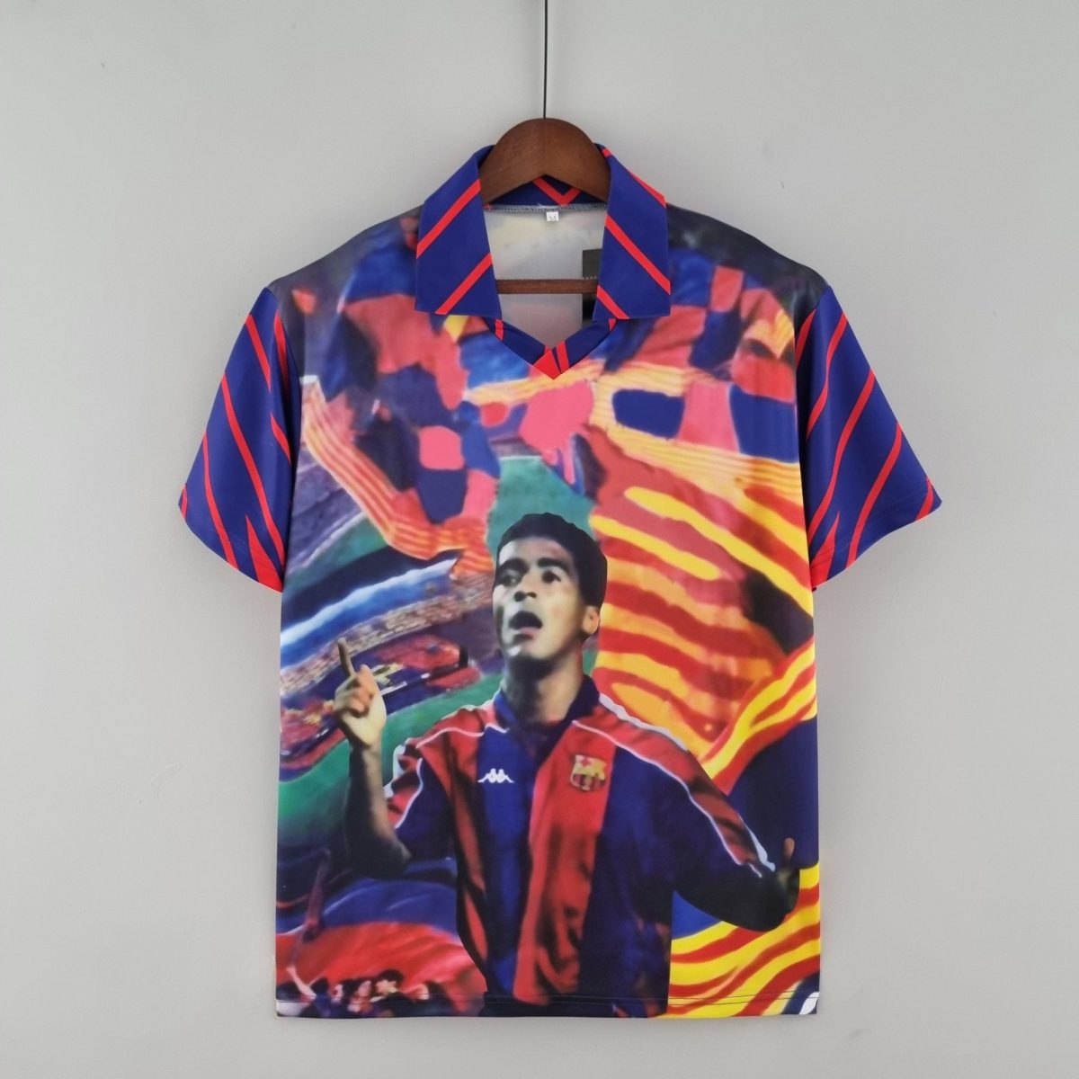 Colorful shirt with blue and red abstract print hanging on a wooden hanger against a gray wall.