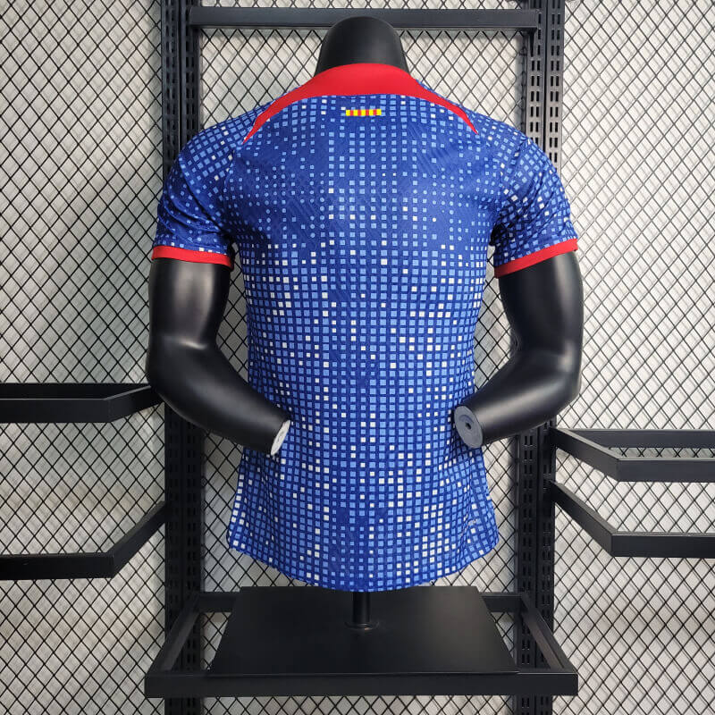barcelona-special-edition-jersey-202324-239769 | UAE SPORT STORE Back view of a blue pixel-pattern athletic jersey on a black mannequin with red collar and red-trimmed sleeves in a retail display.