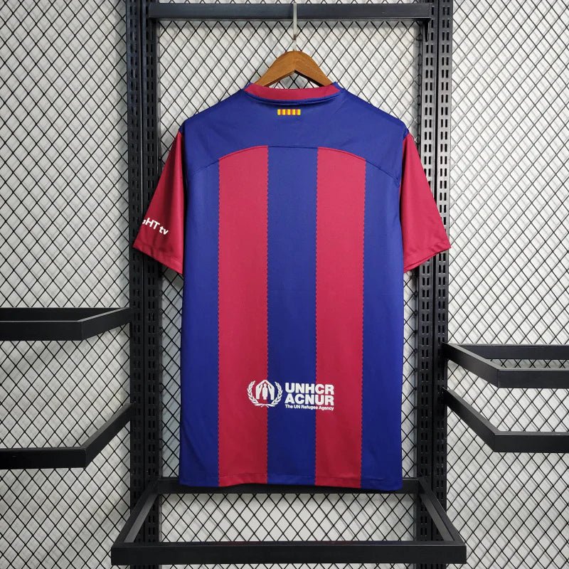 barcelona-x-karol-jersey-202425-176145 | UAE SPORT STORE Back view of a blue and maroon striped sports jersey hanging on a hanger with UNHCR branding visible on the lower back area.