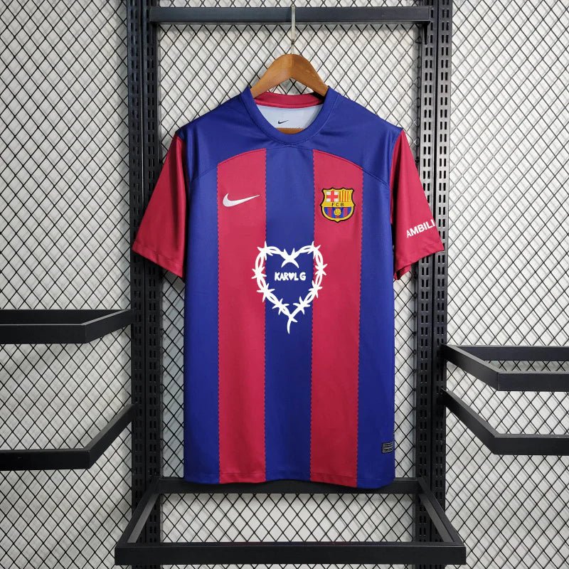 barcelona-x-karol-jersey-202425-469707 | UAE SPORT STORE Barcelona-style soccer jersey hanging on a wooden hanger against a metal rack, blue and red stripes with a team crest on the chest.
