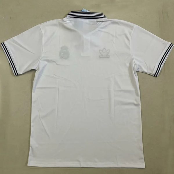 White polo shirt laid flat with a black striped collar and matching black striped sleeve cuffs; faint brand marks visible on the back edge.