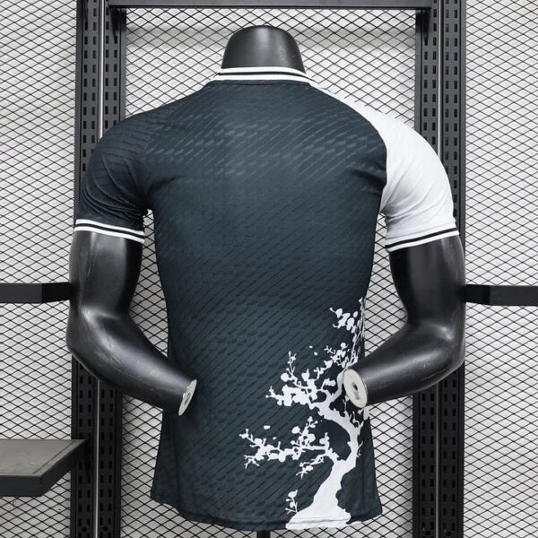 Back view of a headless mannequin wearing a dark teal athletic jersey with white sleeve cuffs and a white tree graphic along the lower right side.