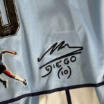 Light-blue sports jersey with a black autograph reading 'DIEGO (10)' beneath a scribbled signature.