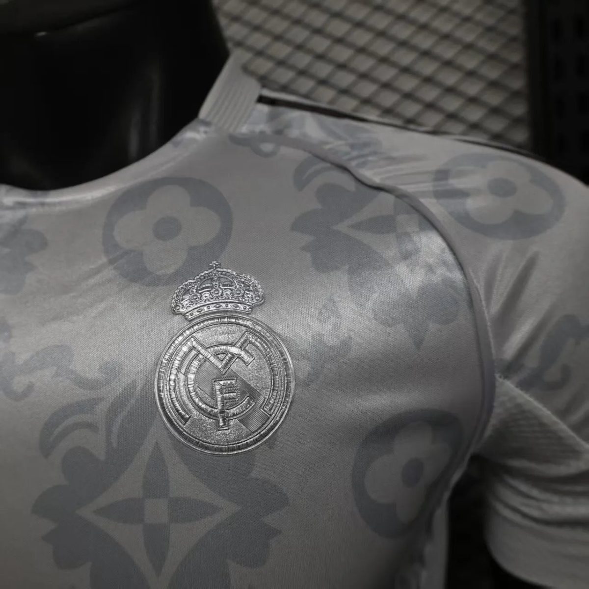 Close-up of a silver Real Madrid crest embroidered on a patterned sports jersey.