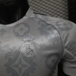 Close-up of a silver Real Madrid crest embroidered on a patterned sports jersey.