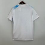 bc5a1bcb_684b85be-fa9e-4325-8505-927b85156bf1 | UAE SPORT STORE White athletic jersey on a hanger with light blue shoulder accents, viewed from the back