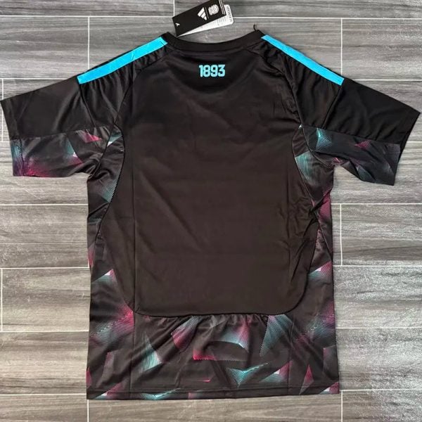 Black athletic jersey with teal '1893' at the back of the neck, blue shoulder stripes, and multicolored geometric panels along the sides and hem, hanging on a hanger.