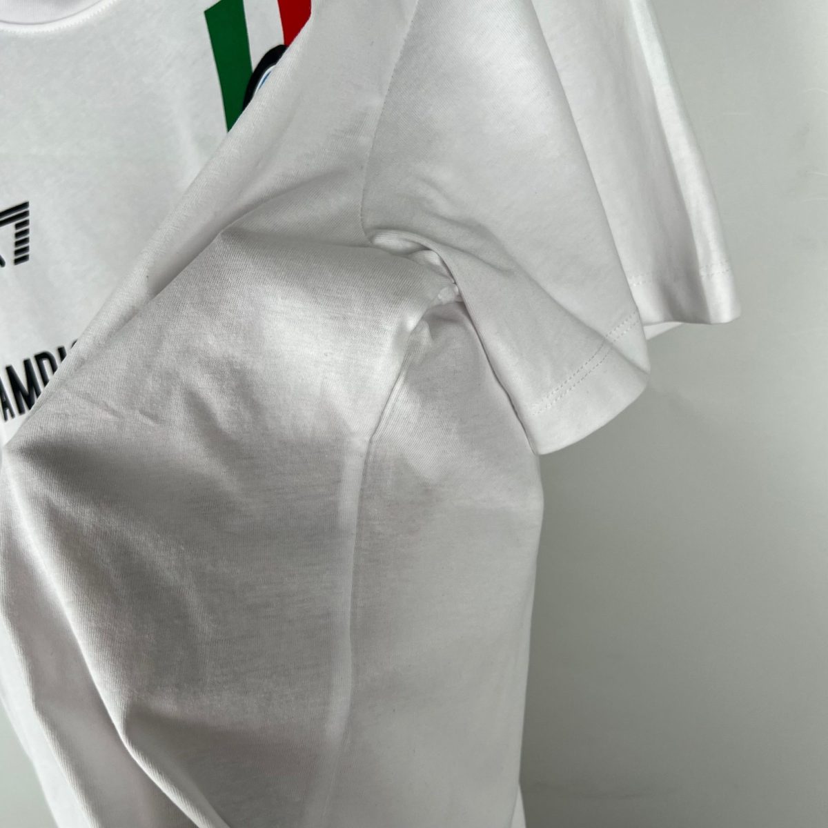 Close-up of white shirt fabric with a small Italian flag detail peeking from behind