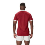 Man seen from the back wearing a red T-shirt with white cuffs and white shorts.