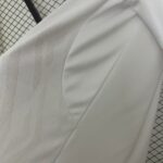 Close-up of white fabric with a pale striped pattern on a grid cutting mat in the background.
