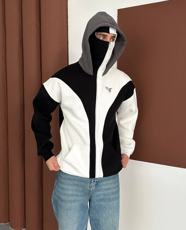 bedogiyimm_472663d360b8300b1573fc7b4dde84f0_1 | UAE SPORT STORE Person wearing a color‑block zip-up jacket (white, black) with a gray hood and face mask, standing indoors by brown walls.