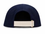 Back view of a navy Dior cap with a beige strap embossed 'Dior' and a gold clasp visible at the right side.
