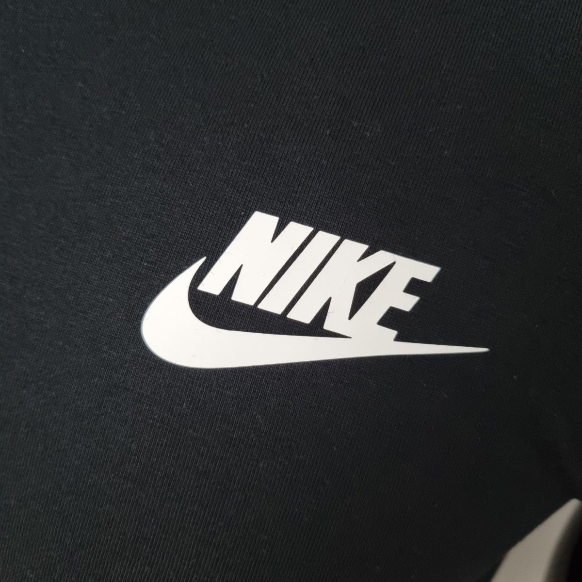 Close-up of dark fabric with a large white word partially visible in the lower right corner.