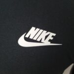Close-up of dark fabric with a large white word partially visible in the lower right corner.
