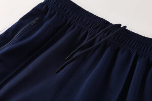 Navy blue joggers with an elastic waist and drawstring, featuring a zippered pocket on the left hip.