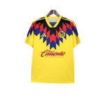 Yellow football jersey with a red, blue, and black zigzag pattern across the chest, featuring the club crest, Adidas logo, and 'Caliente' sponsor.