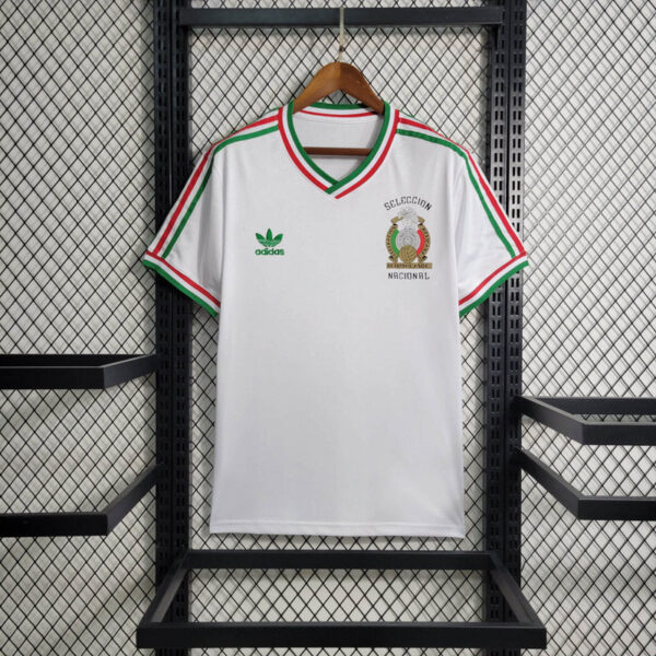 White Mexican national team polo-style jersey on a wooden hanger, Adidas logo on left chest and crest on right, green-red-green trim.
