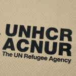UNHCR/ACNUR logo with the text 'The UN Refugee Agency' on a beige background