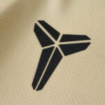 Close-up of a black, stylized three-prong Y-shaped logo on beige fabric.