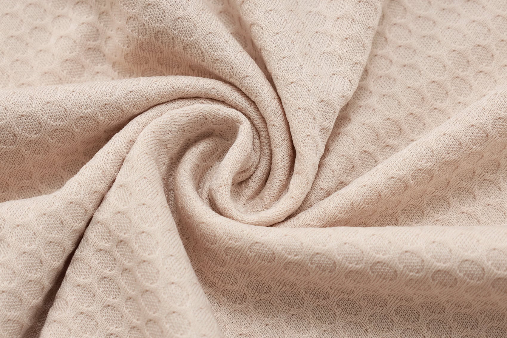 c0159c70 | UAE SPORT STORE Beige textured fabric with a circular dot pattern, folded in soft spirals.