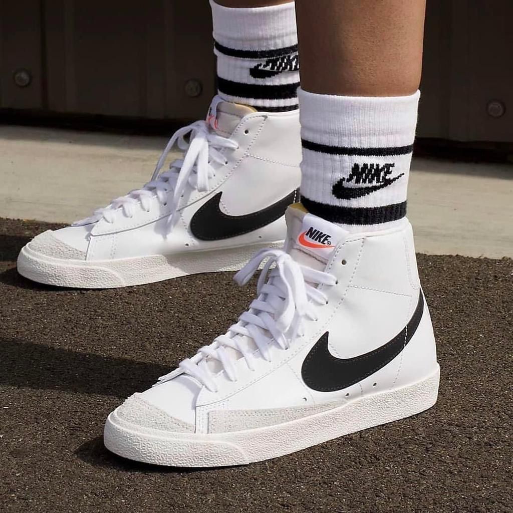 c0292029-bb01-4303-9b31-a9efc0160cea | UAE SPORT STORE White Nike high-top sneakers with black swoosh and white laces, worn with branded white socks on pavement.
