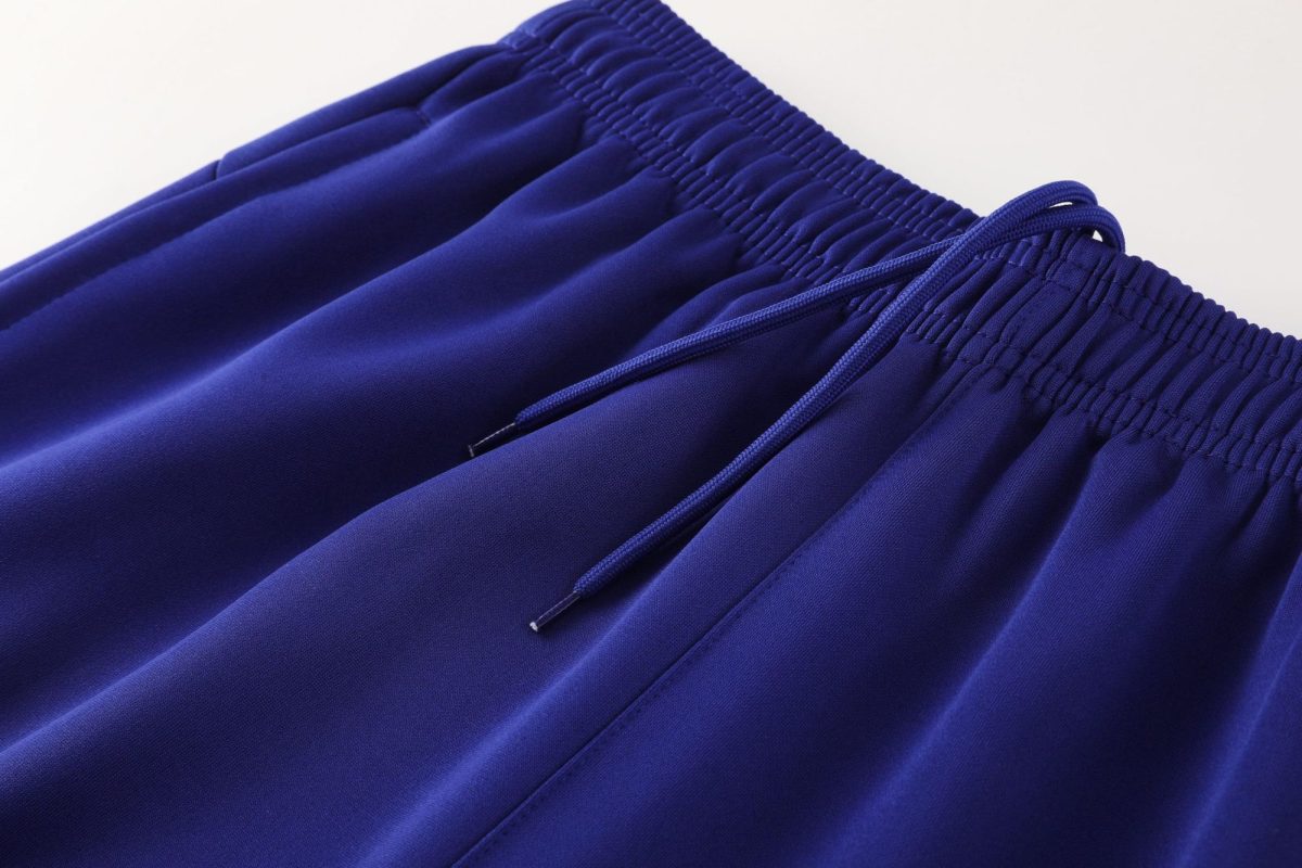 Close-up of blue athletic shorts waistband with elastic and drawstrings on smooth fabric.