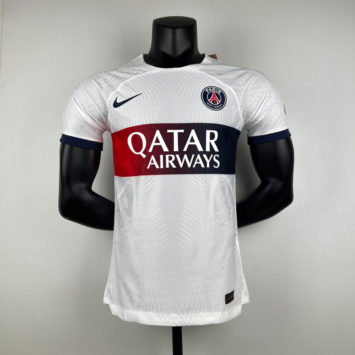 Mannequin wearing a white Paris Saint-Germain jersey with Qatar Airways sponsor, Nike swoosh, and PSG crest on the chest.
