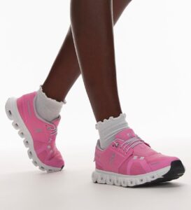 c0994191-972e-492b-afa4-48e978012337 | UAE SPORT STORE Bright pink On running shoes with white chunky soles and white socks on dark legs against a white background.