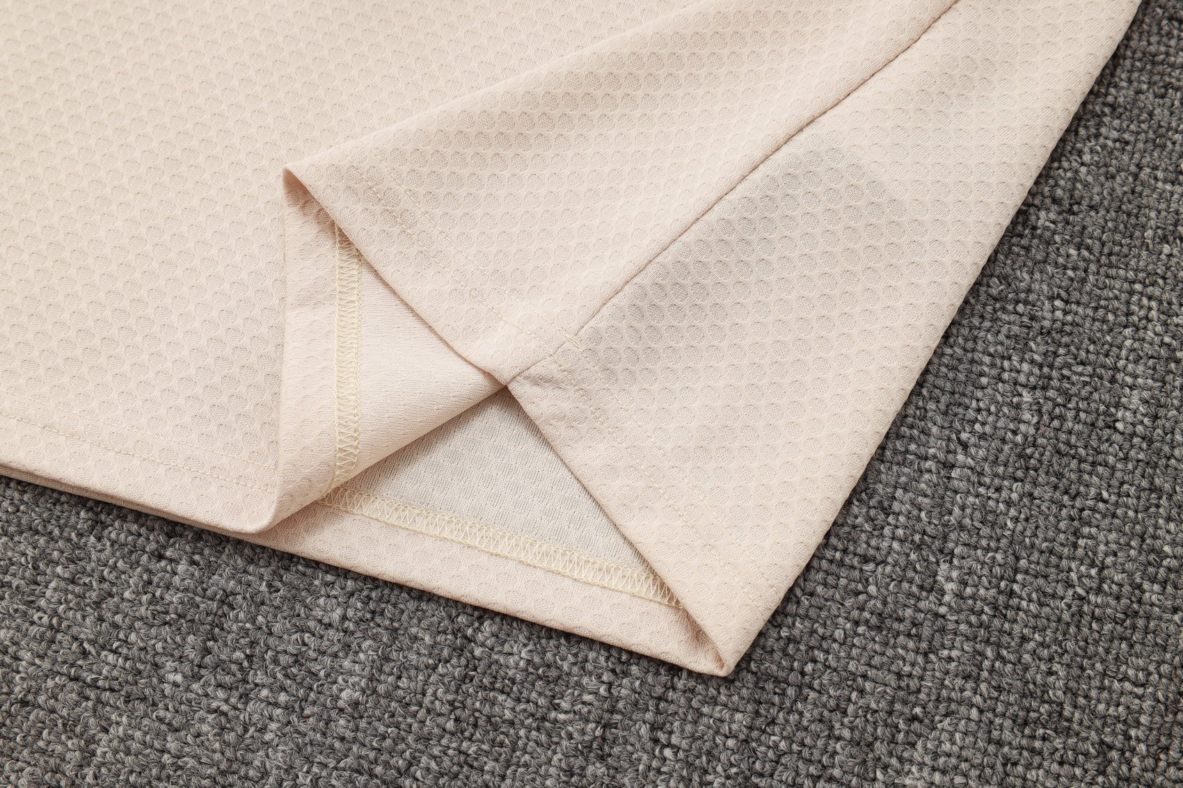 c0a4a0da | UAE SPORT STORE Beige folded towels with a waffle texture laid over a gray carpet.