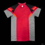 c1572812fa1b6a7b13c617b9 | UAE SPORT STORE Front view of a red and gray athletic jersey with black shoulders and orange accents; small white circular logo at the neckline.