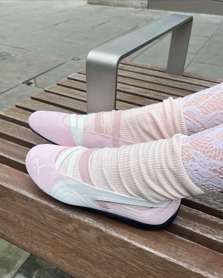c1bfc21e-457d-4350-931e-f93423037d11 | UAE SPORT STORE Pair of light pink slip-on sneakers on a person resting their feet on a wooden bench, wearing pale pink socks and lace leggings.