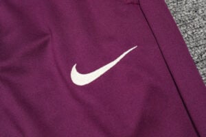 White Nike swoosh logo on purple athletic fabric.
