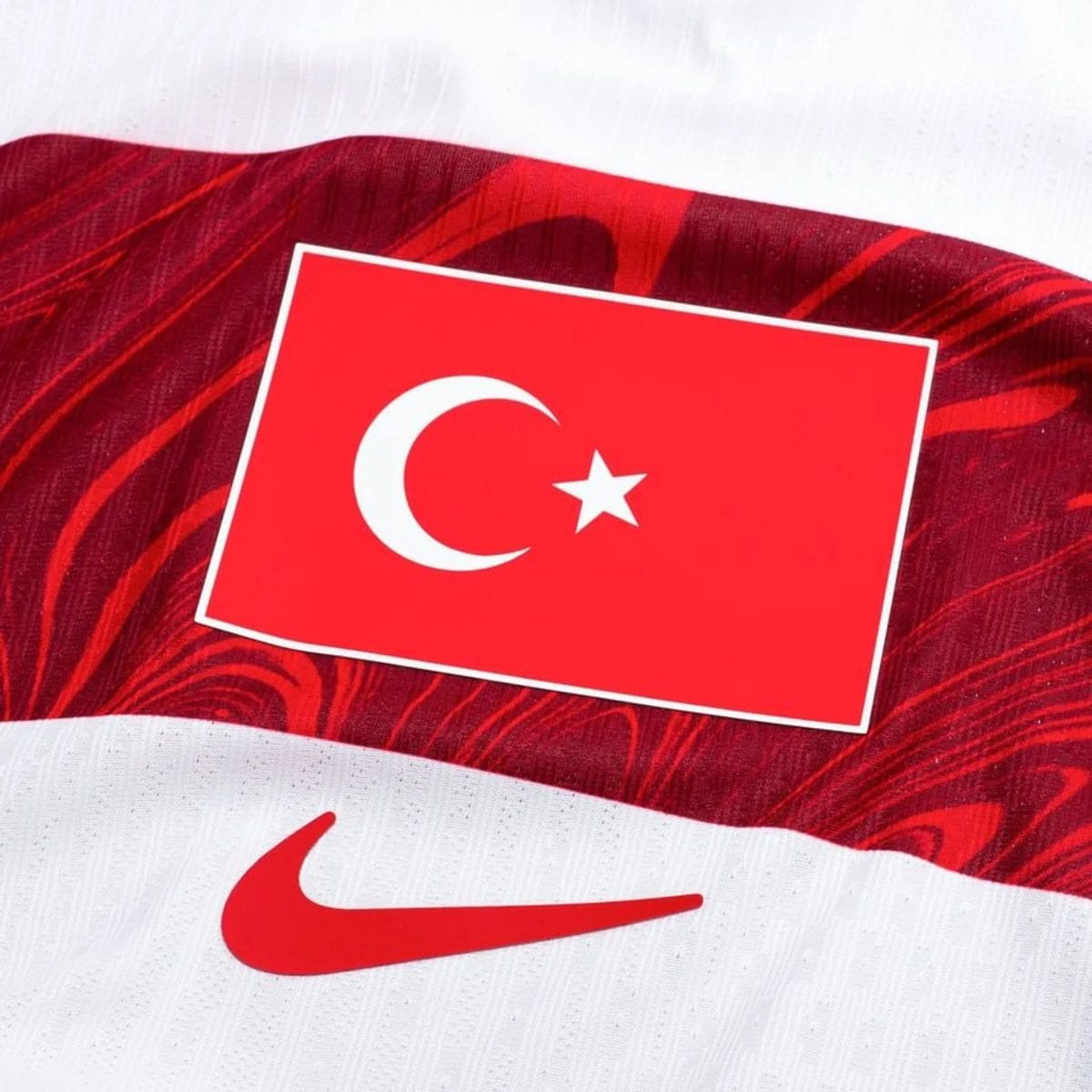 Red card with a white crescent and star (Turkish flag motif) placed on a red, textured background; a portion of a white Nike swoosh appears in the bottom left.