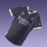 Dark purple football jersey with Emirates Fly Better logo and a green-trim V-neck, floating on a purple gradient background.