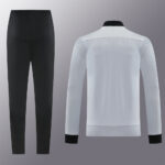 White athletic jacket with black collar and cuffs shown from the back, paired with black athletic pants on the left.