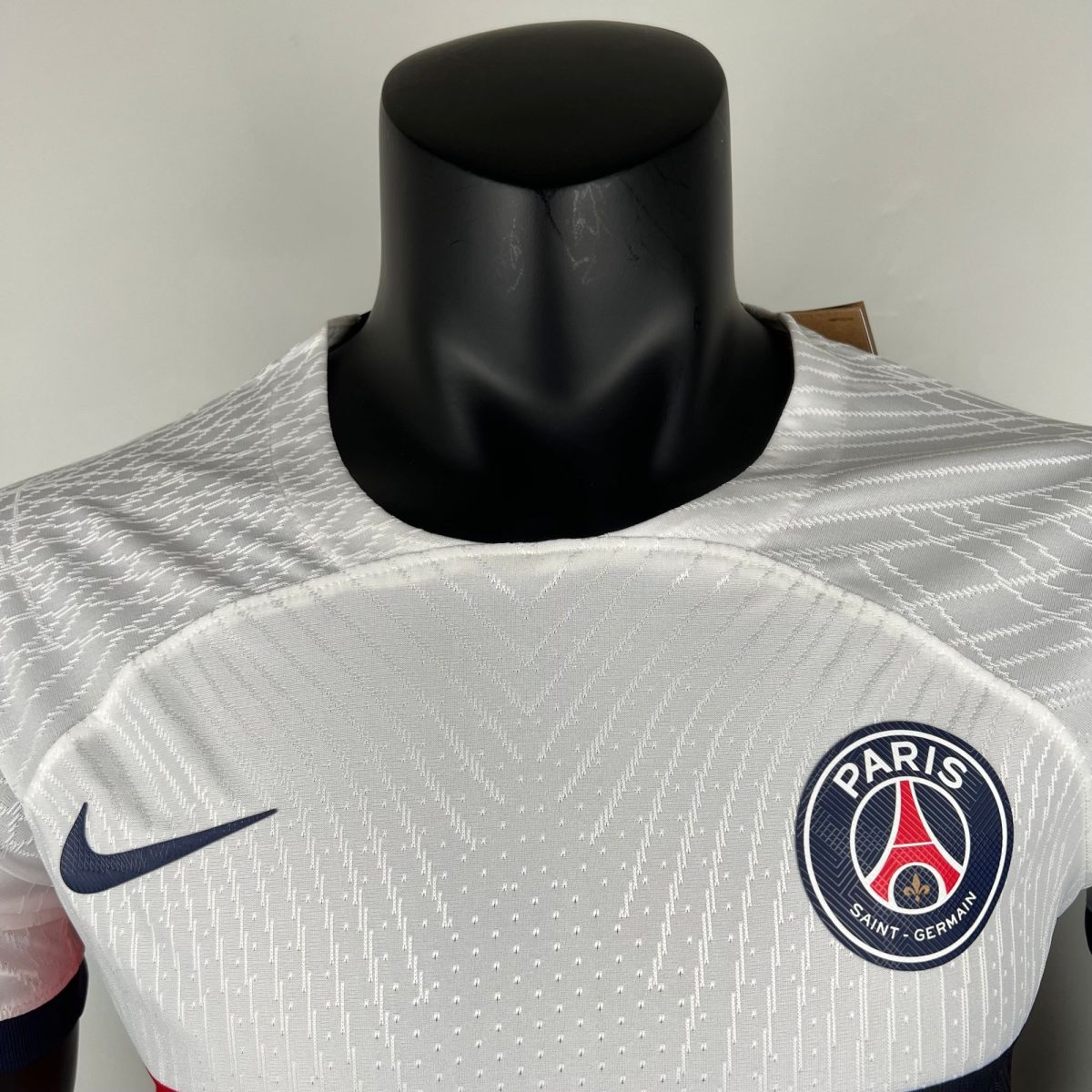 Gray Paris Saint-Germain soccer jersey on a black mannequin displaying the Nike swoosh and PSG crest.